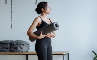 woman in black activewear and holding a yoga mat